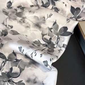 Detail of silk satin scarf showing elegant grey-black floral print and glossy texture
