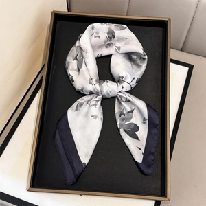 Detail of floral silk scarf tied in a bow on a black tray with gold trim