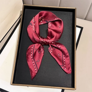 Retro paisley print satin silk scarf in deep red knotted on a luxury display tray