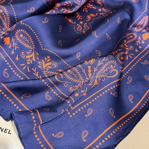 Detail of blue and orange paisley print silk scarf showing soft fabric folds and texture