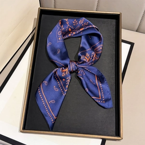 Vintage paisley print silk twilly scarf in navy blue and orange shown on a golden tray