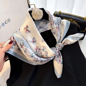 Élégant foulard en soie à motif papillon et broche camélia sur une tenue noire