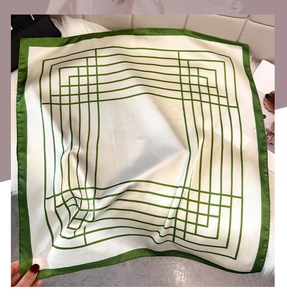 Close-up of geometric silk square scarf with green stripes on plush white rug