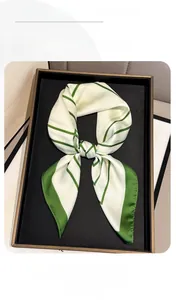 Detail of silk square scarf with green geometric stripes in premium gift packaging