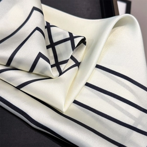 Close-up of geometric striped silk scarf showing the smooth satin texture and drape