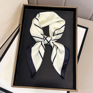 Detail of elegant striped silk scarf with black borders tied in a chic bow on a tray