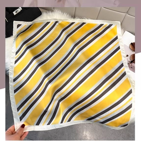 Detail of geometric striped silk scarf in yellow and grey with premium satin texture