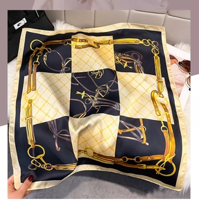 Detail of luxury silk square scarf with classic horsebit and chain patterns on a bag
