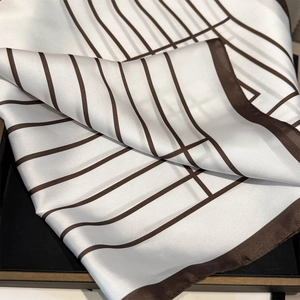 Detailed close-up of geometric striped silk scarf texture and fine hemmed edges
