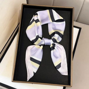 Detail of geometric striped silk scarf showing purple and yellow patterns on a tray
