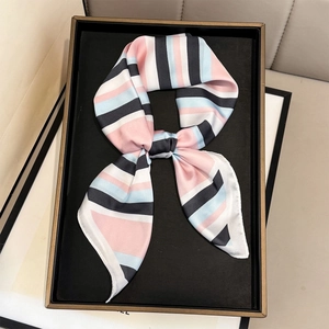 Elegant geometric striped silk scarf tied in a bow on a luxury display tray for women