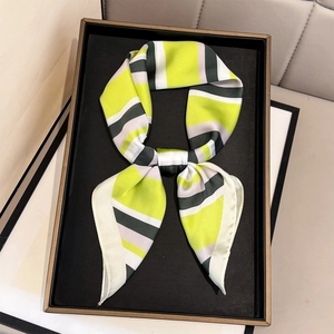 Elegant silk scarf with green and purple geometric stripes in a black display tray