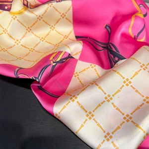 Detail of luxury silk scarf showing vibrant pink chain print and satin fabric texture