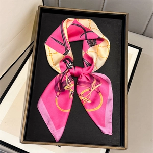 Pink silk-like square scarf with luxury chain print tied in a bow on a black tray