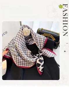 Detailed view of silk scarf with houndstooth and leaf print featuring a burgundy border