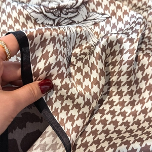 Detail of silk scarf with houndstooth print and floral patterns showing smooth texture