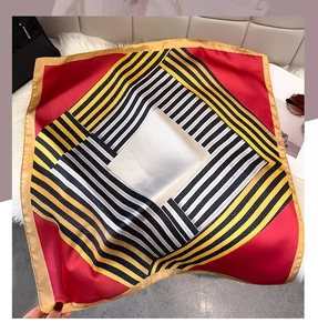 Detailed close-up of geometric striped pattern on silky square scarf with red edges