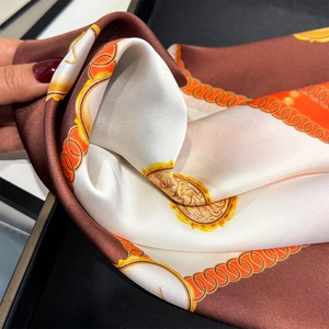 Detail of premium silk scarf showing glossy texture and vintage gold coin pattern