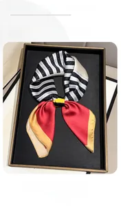 Close-up of geometric striped silk-like scarf with red and yellow panels on a tray