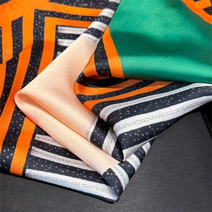 Detail of satin scarf with colorful geometric stripes and polka dots in silk-like texture