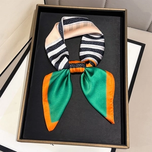 Polished geometric striped silk scarf tied in a bow on a black display tray