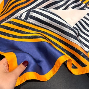 Close-up of geometric striped silk scarf with orange and navy pattern detail