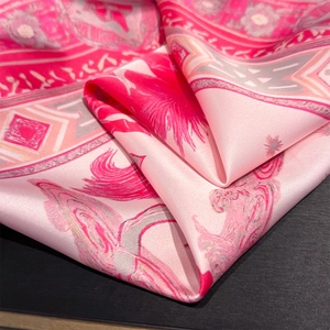 Close-up of pink silk square scarf featuring detailed horse and floral pattern print