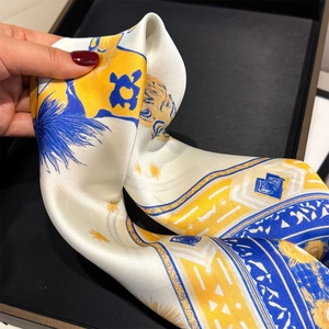 Macro detail of royal blue and yellow lion crest print on glossy silk scarf fabric