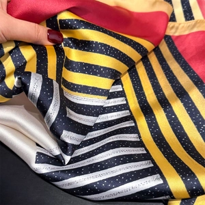 Silky square scarf with geometric stripe pattern in red, yellow, and black silk satin fabric