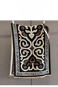 Detailed view of black jacquard winter scarf with floral scroll motifs and beige tassels