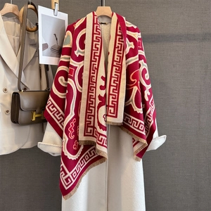 Close-up of winter thick warm scarf featuring red geometric patterns and fringe tassels