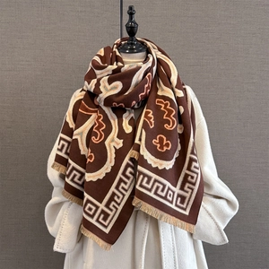 Close-up of brown jacquard scarf with wave patterns and fringe on white wool coat