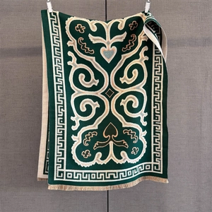 Close-up of ethnic knit scarf featuring dark green baroque patterns and beige tassels