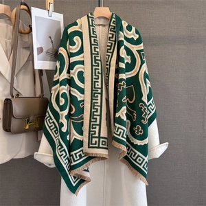 Close-up of a dark green retro knit shawl with geometric patterns and fringe detail