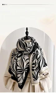 Detail of thick black and white botanical print scarf with soft fringe and warm texture