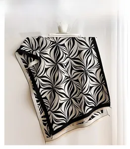 Detail of soft winter scarf showing black and white geometric pattern with fringe edge