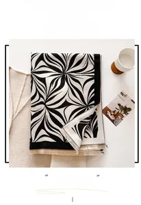 Detail of a thick knitted scarf with black and white swirl patterns and tassel edges
