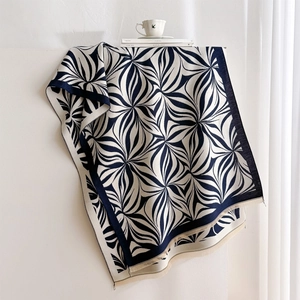 Detailed close-up of thick scarf showing geometric leaf print and fine fringe edges