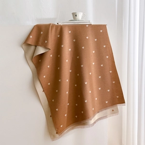 Close-up of heart pattern jacquard scarf with decorative fringe in warm camel tone