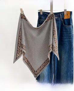 Detail of houndstooth silk scarf with vintage paisley border hanging on clothes rack