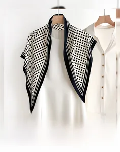 Detail of vintage polka dot silk scarf draped over a white dress on a wooden hanger
