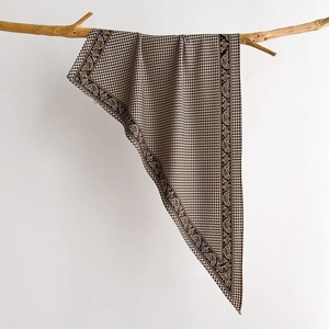 Elegant houndstooth and paisley twill scarf hanging on a natural wooden branch