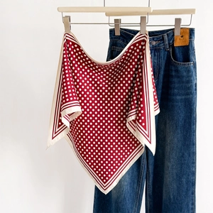 Classic red and white polka dot silk scarf with striped hem hung on denim jeans