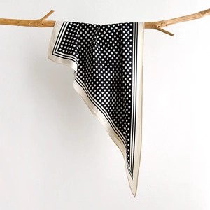 Elegant polka dot silk scarf draped on a natural branch against a soft gray background