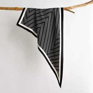 Minimalist black and white geometric pattern silk scarf draped on a wooden branch