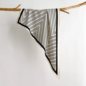 Modern black and white striped triangle scarf draped on a branch for spring fashion