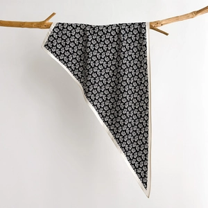 Classic black and white paisley silk scarf draped over a wooden branch against a white wall