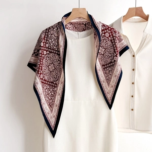 Deep red Paisley silk square scarf styled over white dress on a white background