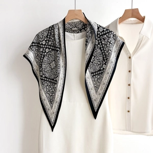 Elegant black and white paisley silk scarf with ethnic patterns on a white hanger