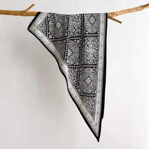 Chic black and white paisley silk shawl displayed elegantly on a natural wooden branch